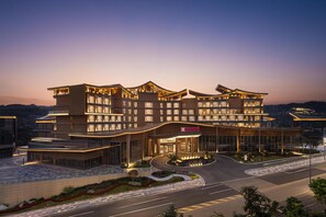 A multi-story hotel with a modern architectural design, featuring a curved entrance and a landscaped area in front. - Hilton Garden Inn Chongqing Bishan (Chongqing)