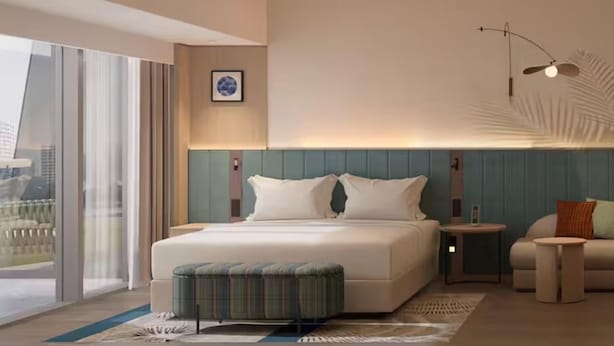 A modern hotel room with a large bed, a seating area, and a view of the city. - Hilton Garden Inn Huangshi Dinosaur Wonderland (Huangshi)