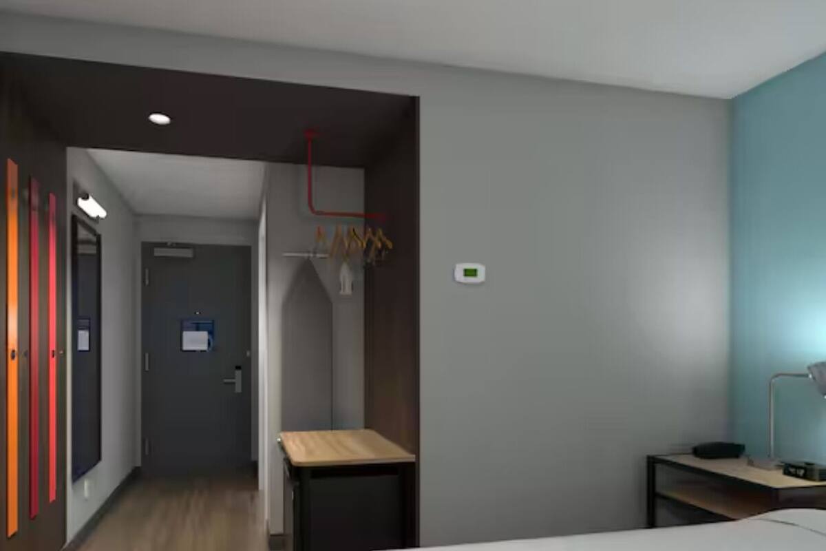 Une chambre d’hôtel moderne équipée d’un lit, d’un bureau et d’une armoire.