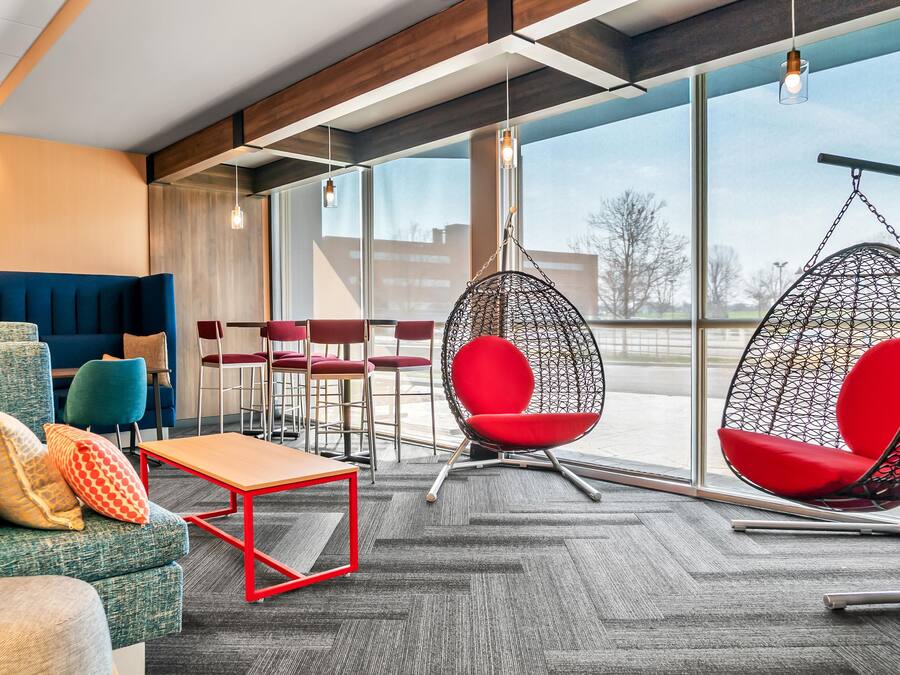 A modern interior with seating arrangements, a hanging chair, and large windows.