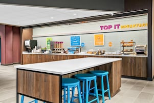 Un desayunador con mostrador, taburetes y diversas opciones de comida.