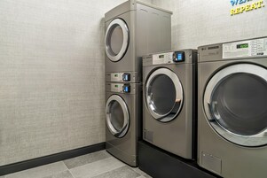 A commercial laundry area with two stacked washing machines and a control panel.