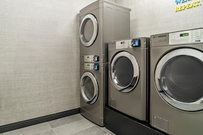 A commercial laundry area with two stacked washing machines and a control panel. - Tru By Hilton Hagerstown (Hagerstown)