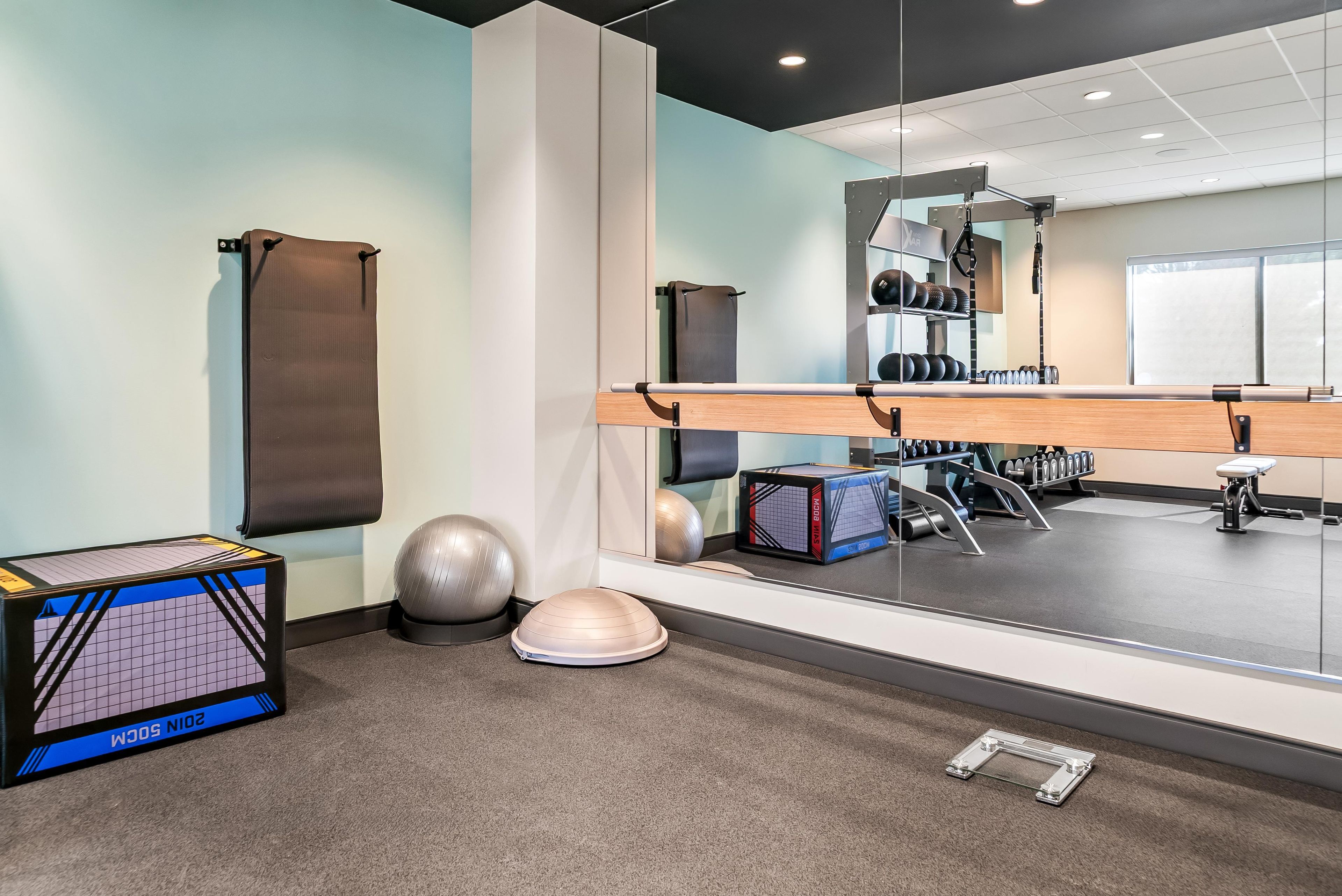 Una palestra con attrezzature per esercizi, uno specchio e una finestra.