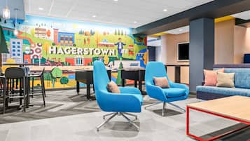 A modern lounge area with blue chairs, a sofa, and a mural depicting Hagerstown.
