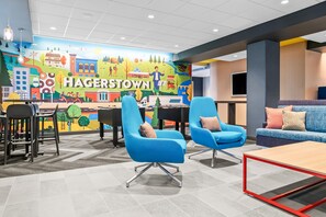 A modern lounge area with blue chairs, a sofa, and a mural depicting Hagerstown. - Tru By Hilton Hagerstown (Hagerstown)