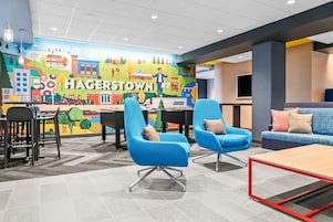 A modern lounge area with blue chairs, a sofa, and a mural depicting Hagerstown.