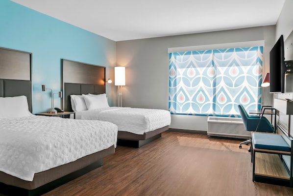 A hotel room with two beds, a desk, a chair, a TV, and a window with patterned curtains. - Tru By Hilton Hagerstown (Hagerstown)