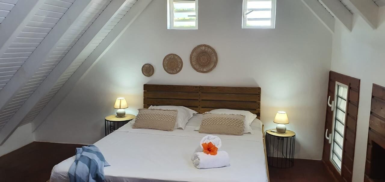 Une chambre à coucher avec un plafond en pente, un lit en bois, deux tables de chevet avec des lampes et une petite fenêtre.