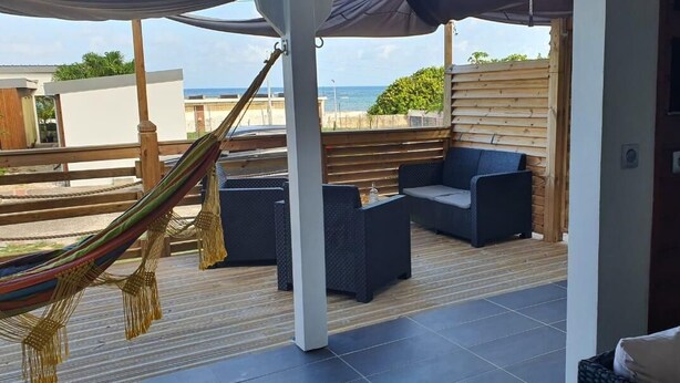 Un espace extérieur aménagé, abrité et doté d’un hamac, de fauteuils confortables et offrant une vue sur la mer.