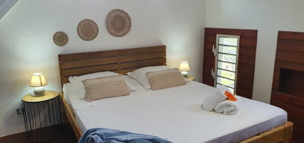 A neatly made bed with two pillows and a blanket, a bedside lamp, and a wall-mounted decorative item.