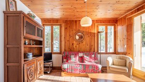 A wooden-paneled room with a sofa, a chair, a cabinet, and a table.