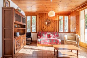 Um quarto com painéis de madeira, um sofá, uma poltrona, um armário e uma mesa.