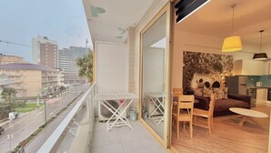 Un balcon avec une table et des chaises, une vue sur la ville et une cuisine équipée d’appareils électroménagers modernes.