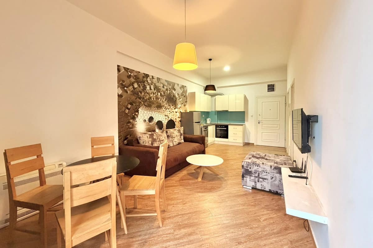Un espacio habitable compacto con comedor, un sofá, una mesita y una cocina al fondo.