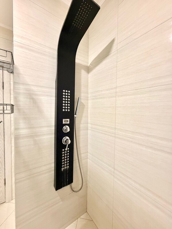 En modern dusch med en böjd design, ett handhållet duschmunstycke och knappar för att styra inställningarna.