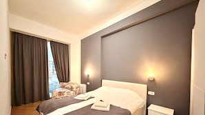 Une chambre à coucher avec un grand lit, deux tables de chevet, une chaise et une fenêtre avec des rideaux.