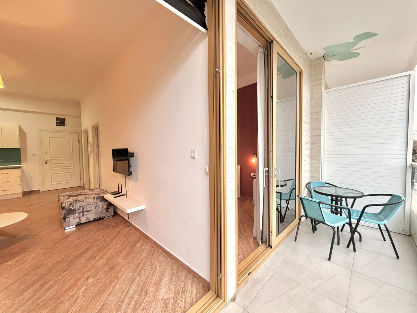 A modern apartment with a living room, dining area, and a sliding glass door leading to a balcony with outdoor seating.