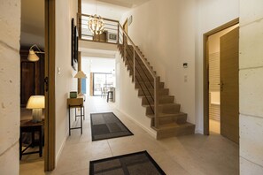 Ein Flur mit Treppe, einer Lampe, einem Teppich und einer Tür.