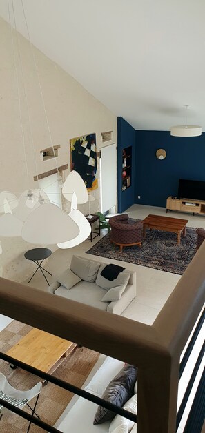 Ett modernt vardagsrum med en soffa, ett soffbord, en tv och en bokhylla.