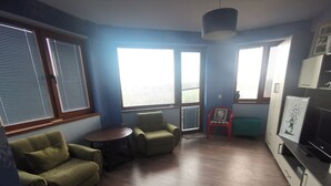 A living room with a sofa, chairs, a small table, and a TV.