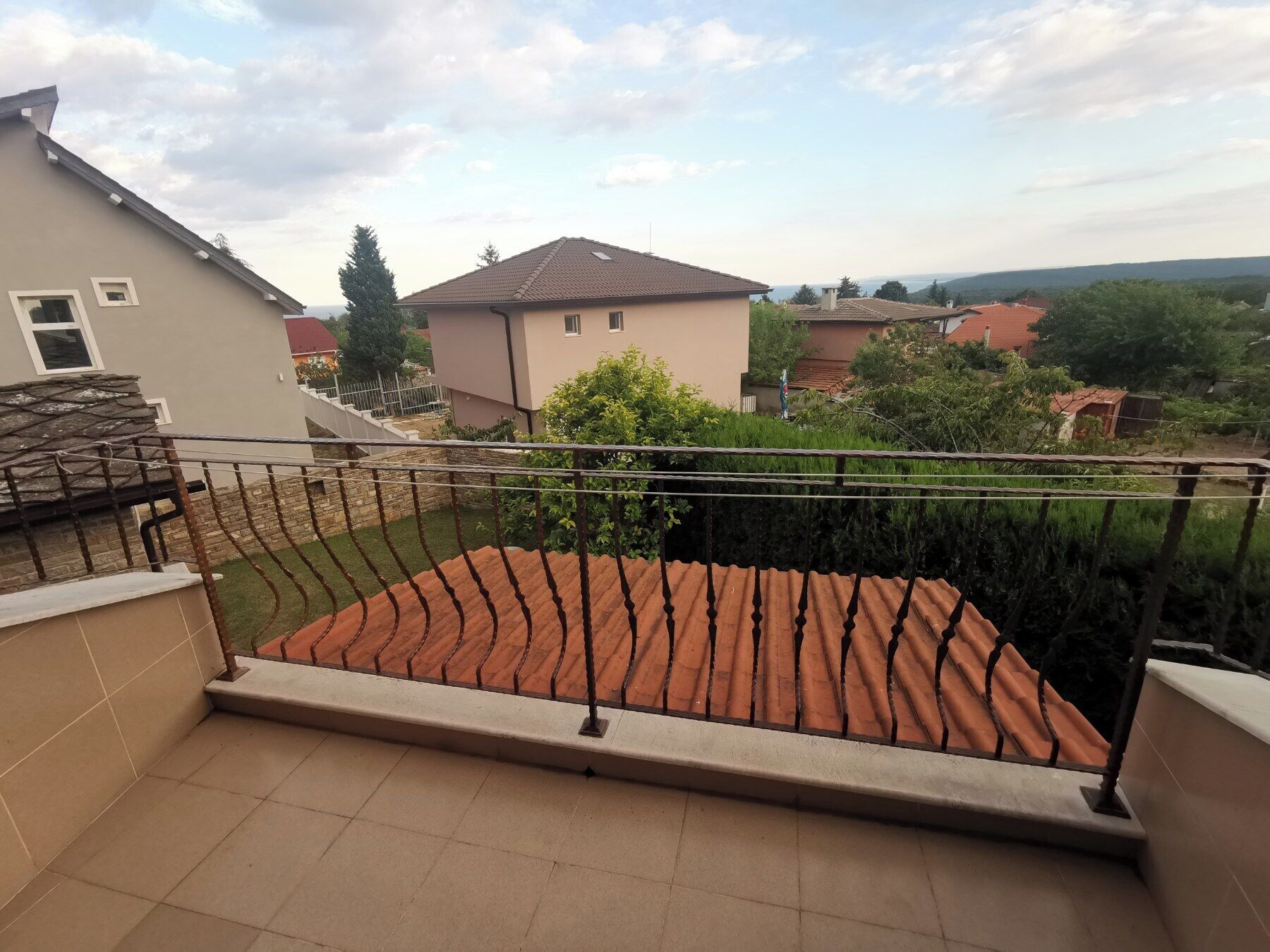A balcony with a tiled floor and a metal railing.