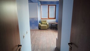 A room with a wooden floor, a blue rug, a green armchair, and a small table.