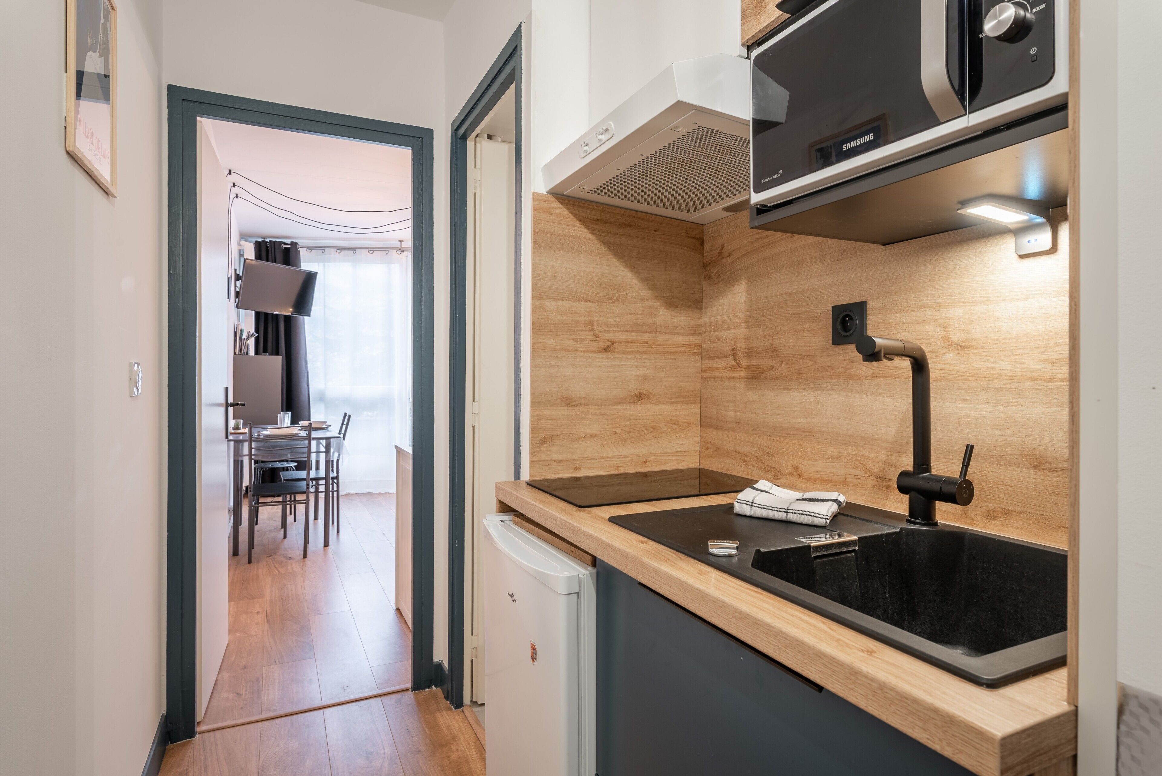 A compact kitchen with a built-in microwave, a sink, and a compact refrigerator.