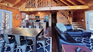 Ein Holzblockhaus im Inneren mit Essbereich, Küche und Wohnzimmer.