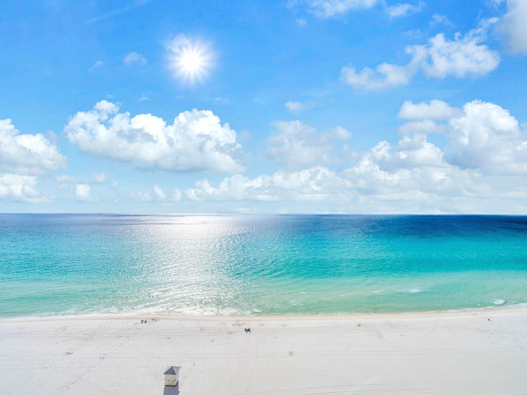 A beach with clear turquoise water, a white sandy shore, and a small lifeguard hut.