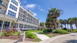 A multi-story hotel with balconies, a landscaped garden, and palm trees. - Winter Rental MB Boardwalk, Dining & Fun Nearby + 100 Dollar Resort credit (Myrtle Beach)