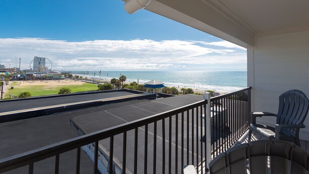 A balcony with a view of the beach and ocean, featuring a railing, chairs, and a table. - Winter Rental MB Boardwalk, Dining & Fun Nearby + 100 Dollar Resort credit (Myrtle Beach)