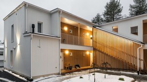 Moderni kaksikerroksinen rakennus, jossa on puinen julkisivu ja parveke.