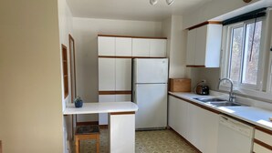 A compact kitchen with white cabinets, a built-in refrigerator, a sink, and a window with blinds.
