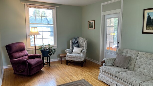 A living room with a purple armchair, a floral armchair, a sofa, and a floor lamp.