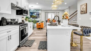 Une cuisine moderne avec des meubles blancs, une cuisinière en acier inoxydable et un grand îlot central doté de tabourets de bar.