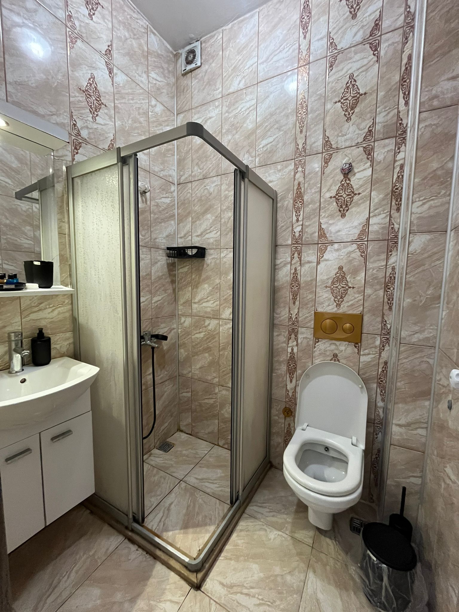 A bathroom with a shower enclosure, a toilet, and a sink.