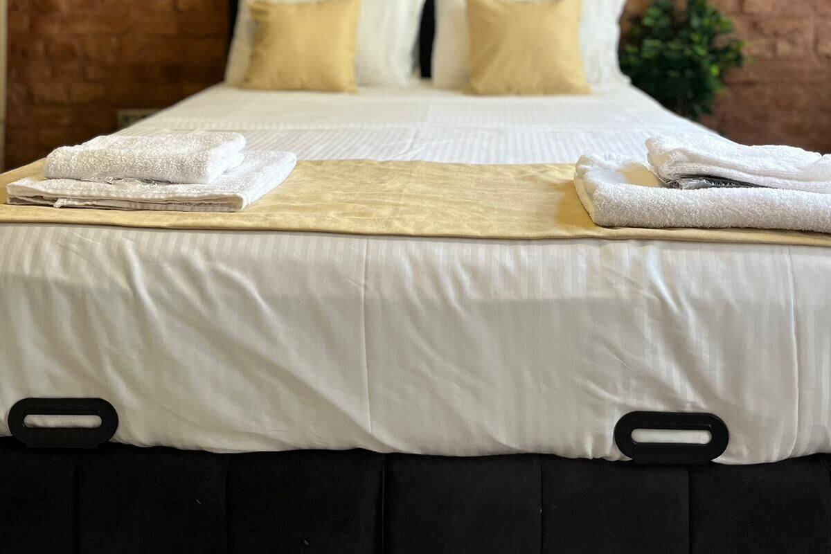 A neatly made bed with white linens and a decorative pillow arrangement.