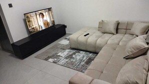 Un salon moderne avec un canapé beige, un meuble de rangement noir et un tapis à motifs.