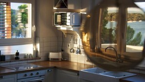 A kitchen with a stove, oven, sink, and a window overlooking a body of water. - Casa Bel Mare (Jelsa)