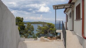 A coastal building with a balcony overlooking a body of water and trees. - Casa Bel Mare (Jelsa)