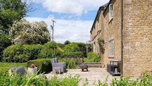 A stone building with a garden patio featuring outdoor furniture and a fire pit. - Spacious Home, Hot Tub, Gym, Games Room & Garden (Hardington Mandeville)
