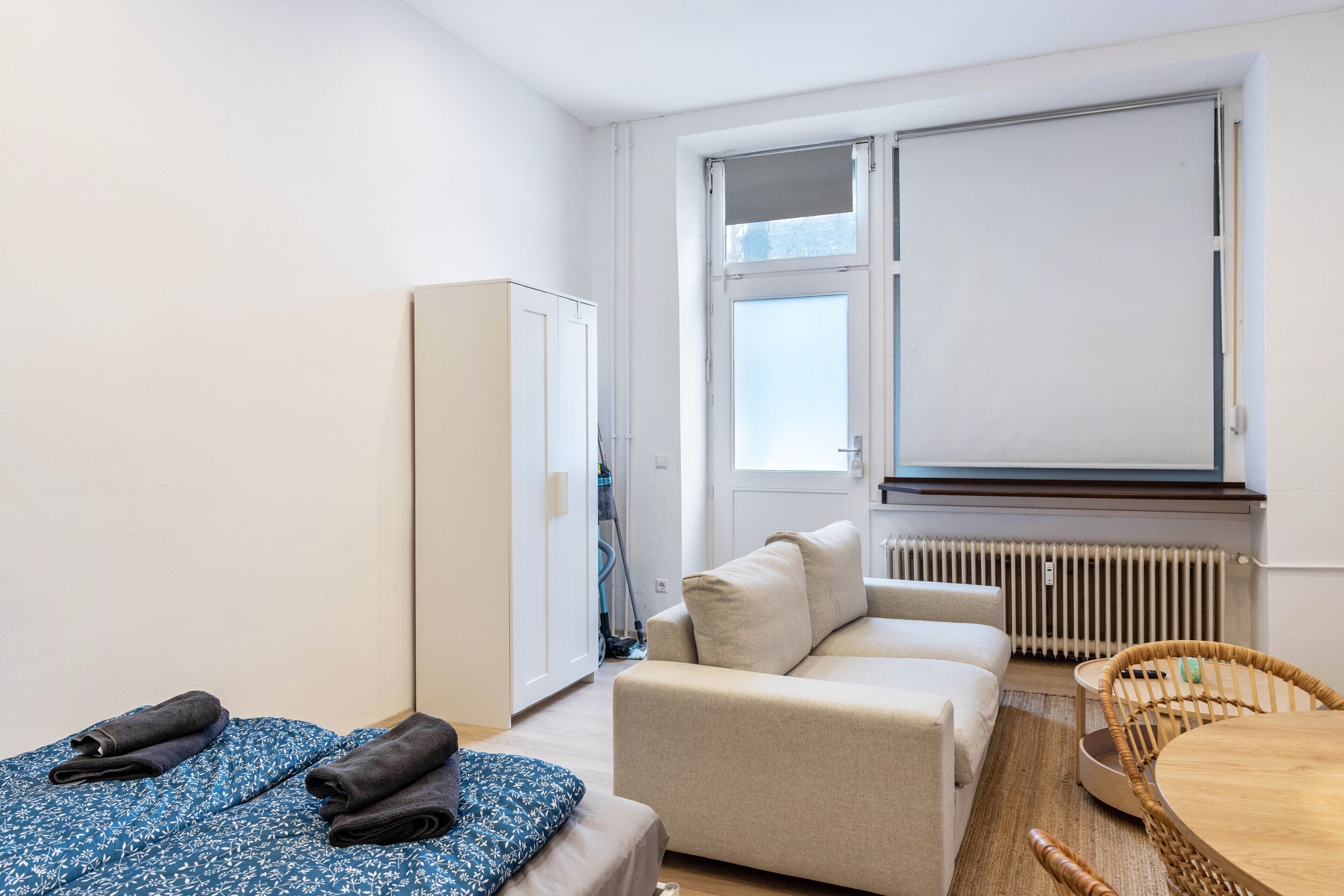A room with a bed, a sofa, a table, and a window.