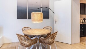A dining area with a round table and wicker chairs, a hanging light fixture, and a wall-mounted clock. - Cozy Apartment in Berlin-Wedding (Berlin)