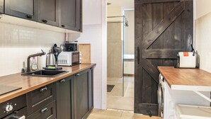 A kitchen with dark cabinets, a wooden countertop, a sliding barn door, and a washing machine. - Cozy Apartment in Berlin-Wedding (Berlin)