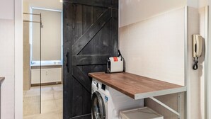 A laundry area with a washing machine, a drying rack, and a wooden countertop. - Cozy Apartment in Berlin-Wedding (Berlin)