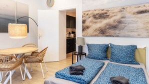 A modern room with a bed, a dining table, chairs, a lamp, a clock, and a large painting. - Cozy Apartment in Berlin-Wedding (Berlin)