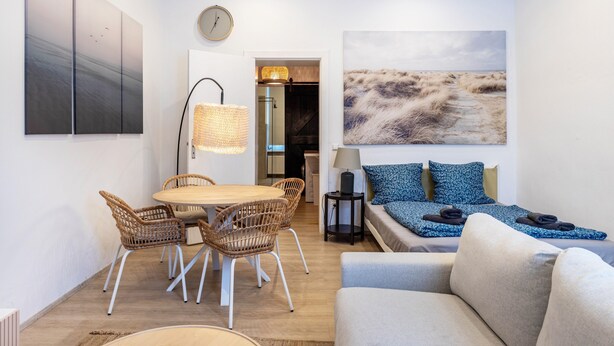 A modern interior with a dining area, a sofa, and a painting of a beach. - Cozy Apartment in Berlin-Wedding (Berlin)