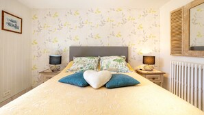 Un dormitorio ordenado con una cama, dos mesitas de noche, un radiador y un espejo.