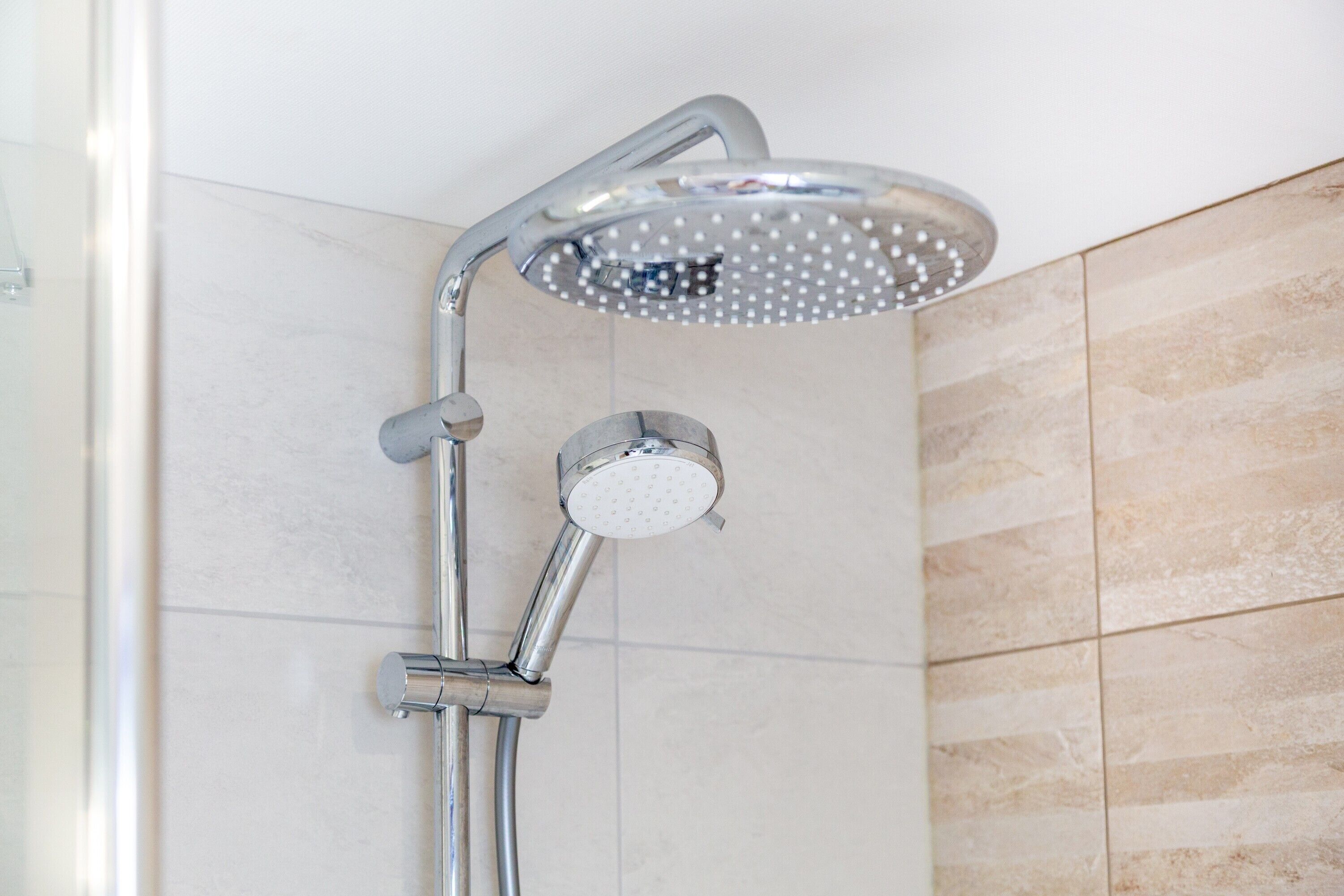 A shower with a handheld showerhead and a fixed overhead showerhead.